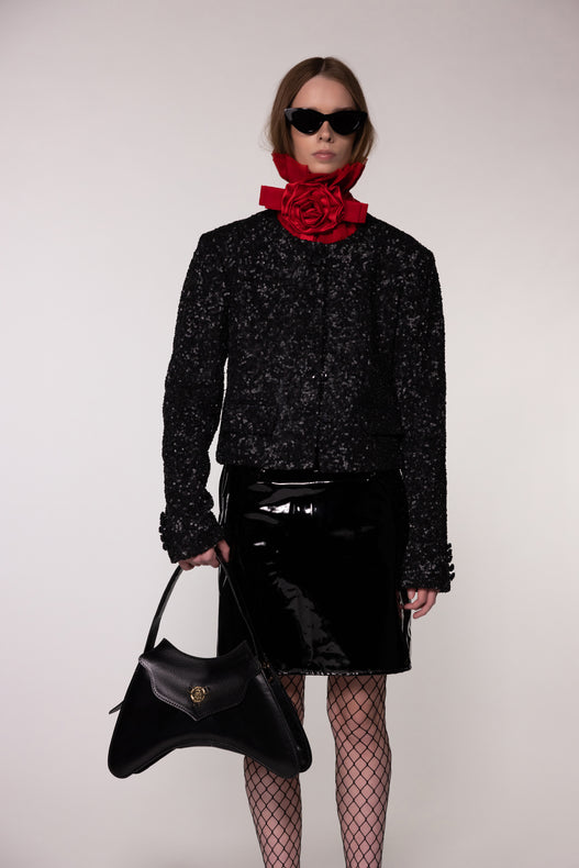 Model wearing the Helen Anthony red organza neck frill with detachable satin flower tie, styled with PU-coated high shine leather skirt and black leather small shoulder bag