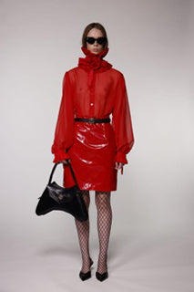 Model wearing the Helen Anthony red organza neck frill with detachable satin flower tie, styled with a sheer red silk organza shirt, PU-coated high shine leather skirt and black leather small shoulder bag