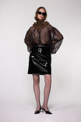 Model wearing the Helen Anthony black organza neck frill with detachable satin flower tie, styled with a sheer brown silk organza shirt and PU-coated high shine leather skirt
