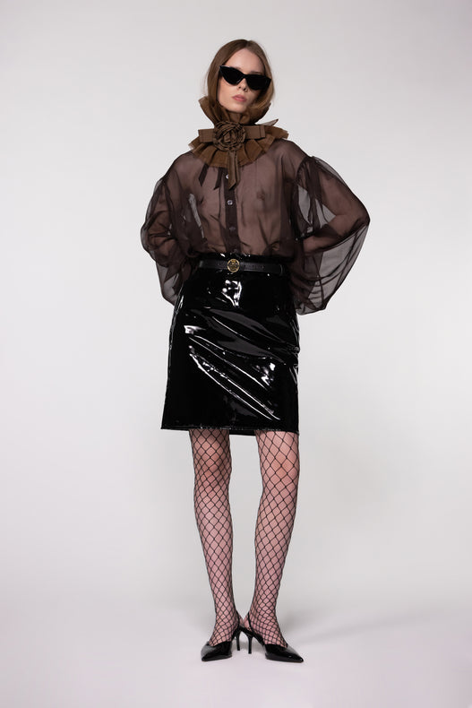 Model wearing the Helen Anthony black organza neck frill with detachable satin flower tie, styled with a sheer brown silk organza shirt and PU-coated high shine leather skirt