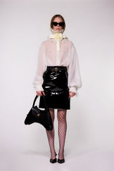 Model wearing the Helen Anthony white organza neck frill with detachable satin flower tie, styled with a sheer white silk organza shirt, and PU-coated high shine leather skirt 